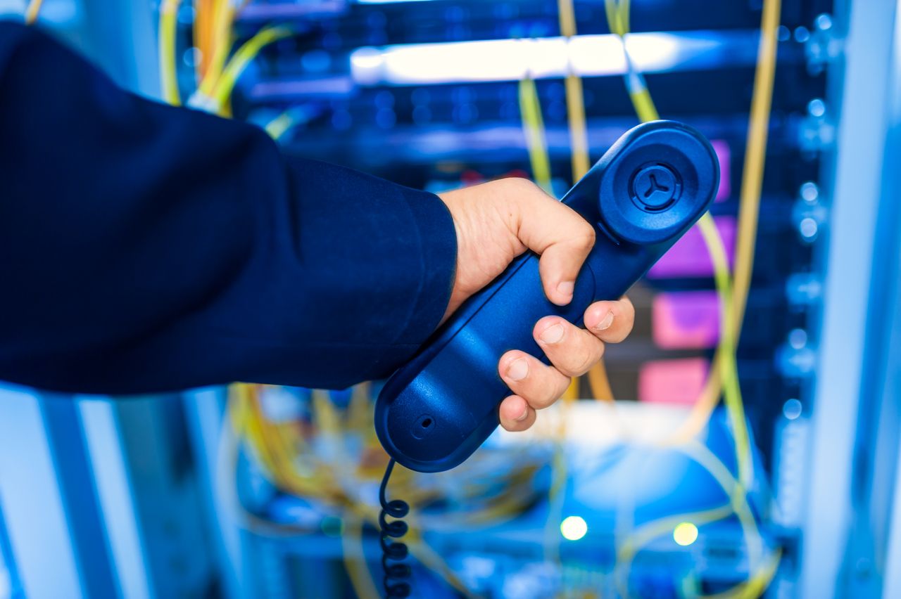 The Art of Drawing Readers In: Your attractive post title goes here Close-up of a hand holding a telephone receiver in a server room emphasizing technology.