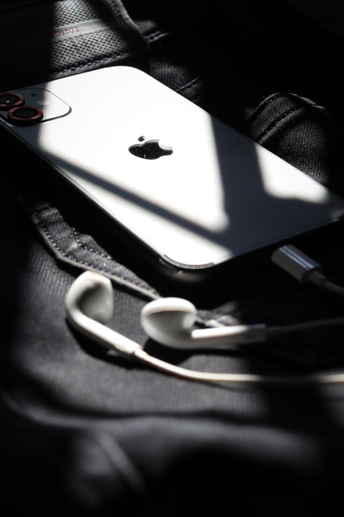 Artistic close-up of a smartphone and earbuds with dramatic lighting. Perfect for tech lifestyle themes.